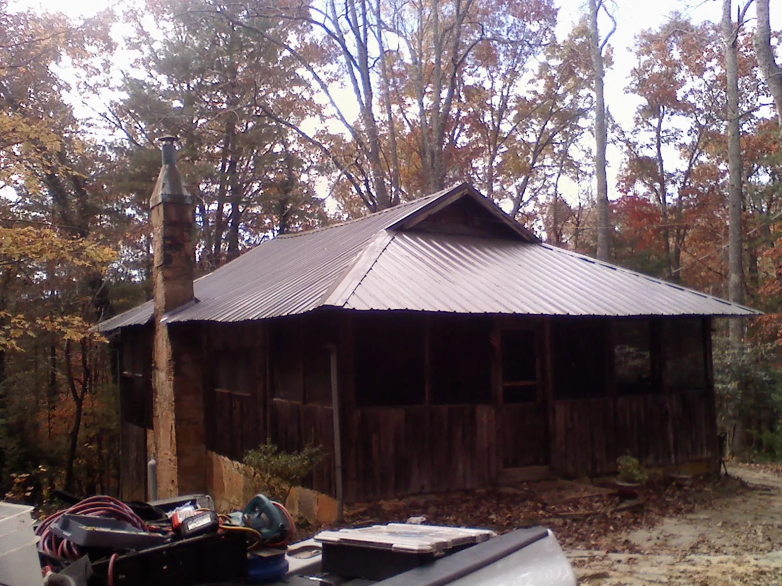 Brown metal hip roof on an old cabin with a stone chimney in Rockville