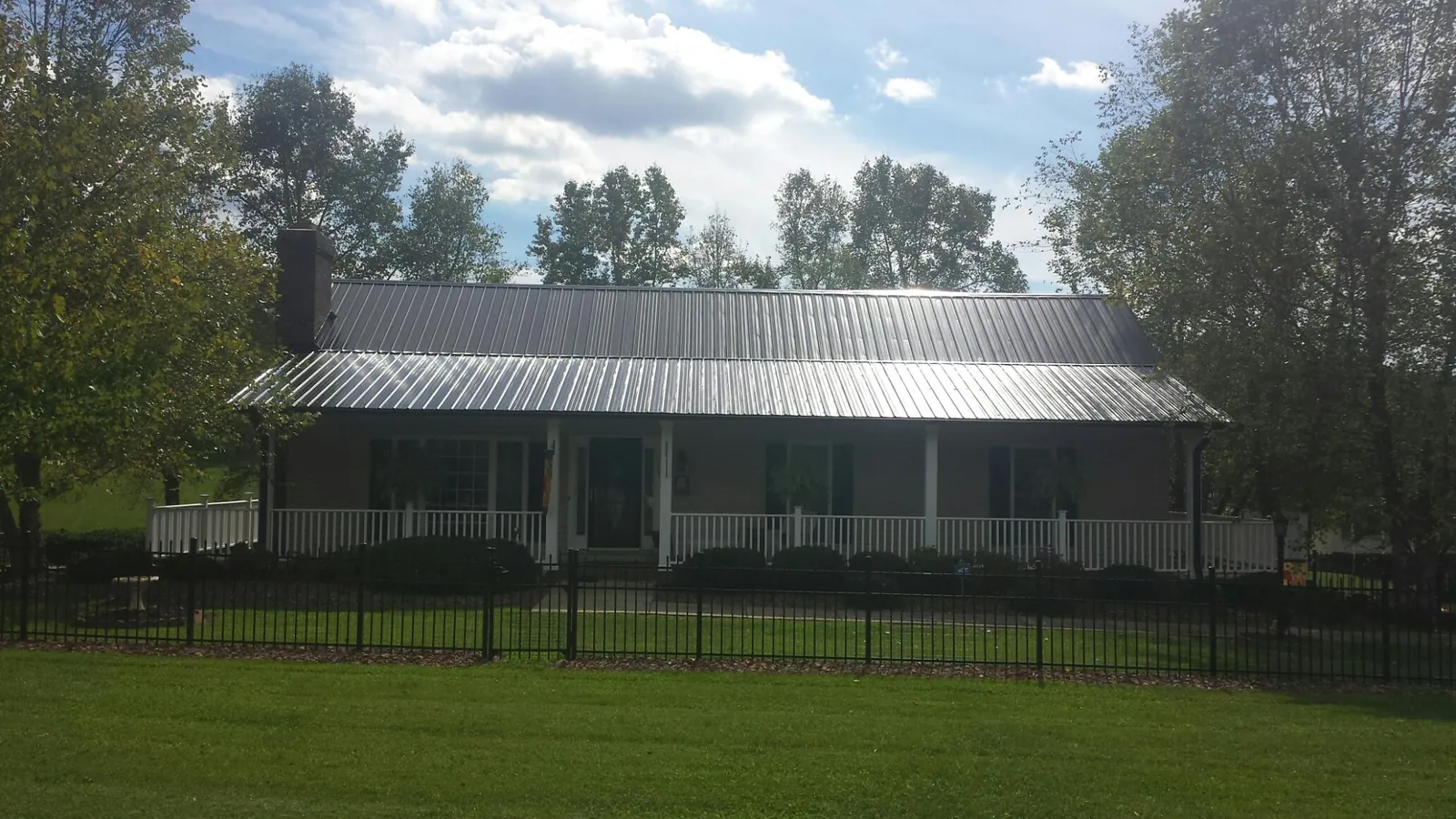 Gray metal roof on a brick ranch with a full width front porch — Gutter Guard Installation work by our crew in Rockville