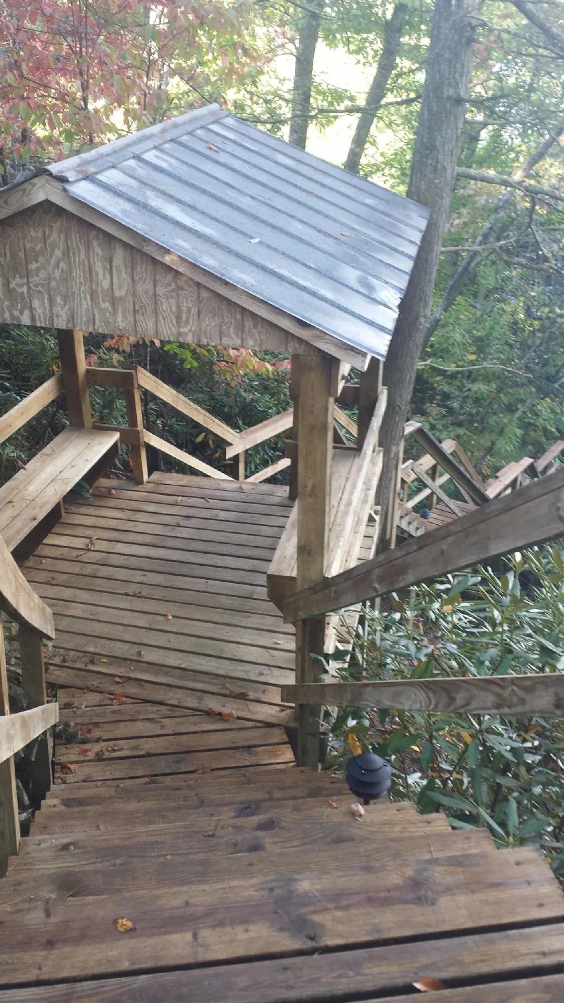 Metal roofed shelter over wooden steps on a wooded walkway — Skylight Repair & Installation work by our crew in Rockville